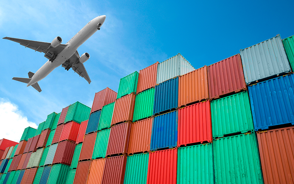 Cargo containers stacked at a port with an airplane flying above the sky